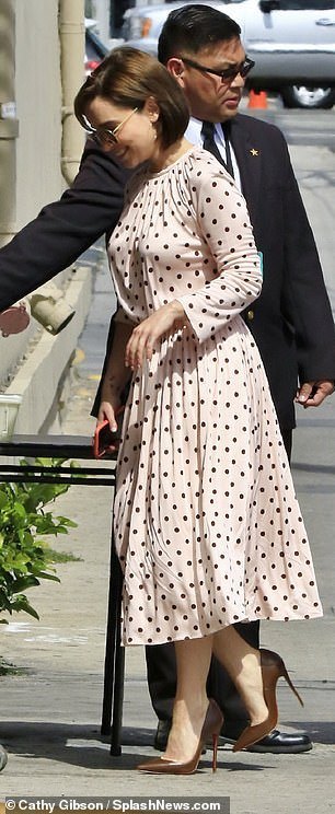 Beaming: Emilia flashed a big grin and a wave as she headed in through the stage door