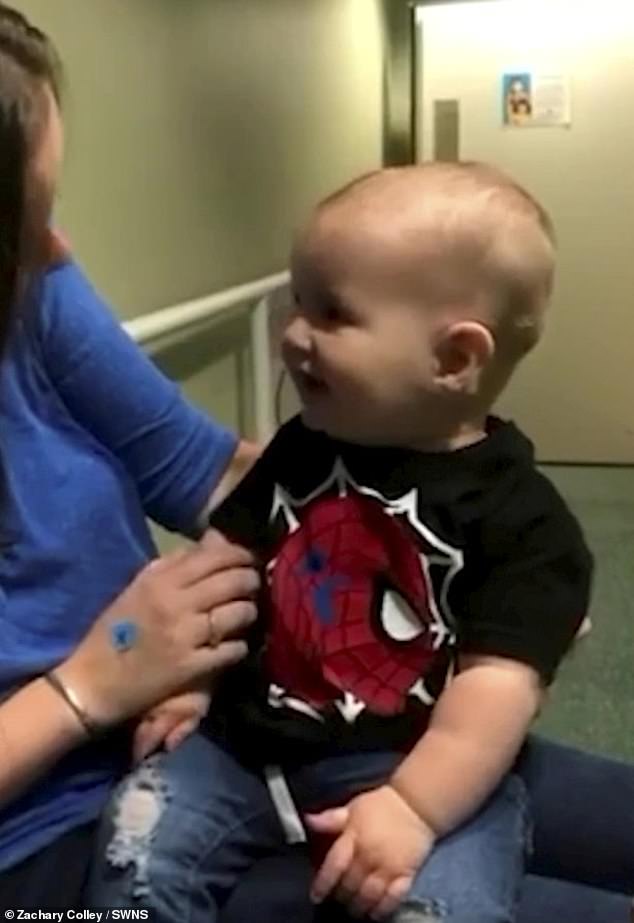 The infant gives his mother a big smile and his father Zachary, 30, begins to speak to him