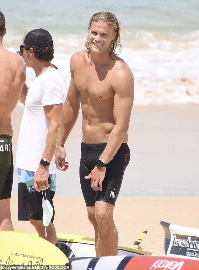 Baring it all: The 27-year-old was all smiles as he walked on the beach shirtless wearing nothing but his triathlon shorts and watch