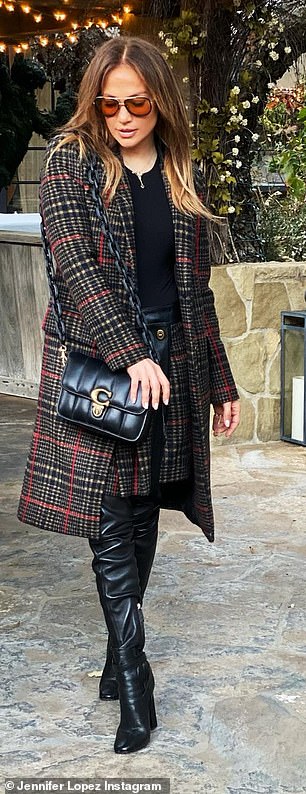 Staying warm: Lopez sported a black top underneath a sizable plaid overcoat while posing for the shots