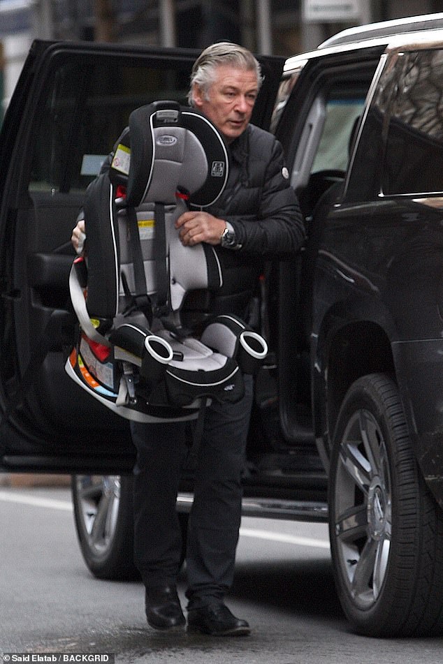 Organizing: The father-of-seven then proceeded to take out one of his children's car seats from the back of the black Cadillac Escalade