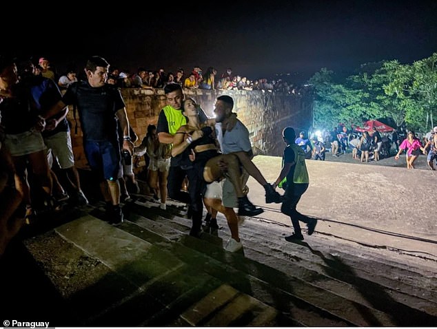 A woman is escorted out of a Paraguayan concert venue after a shooting which left two people dead and four others wounded