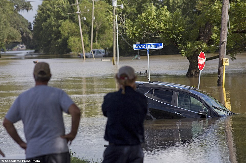 Residents survey the flood water on Old Jefferson Highway at Bayou Manchac in Prairieville on Tuesday