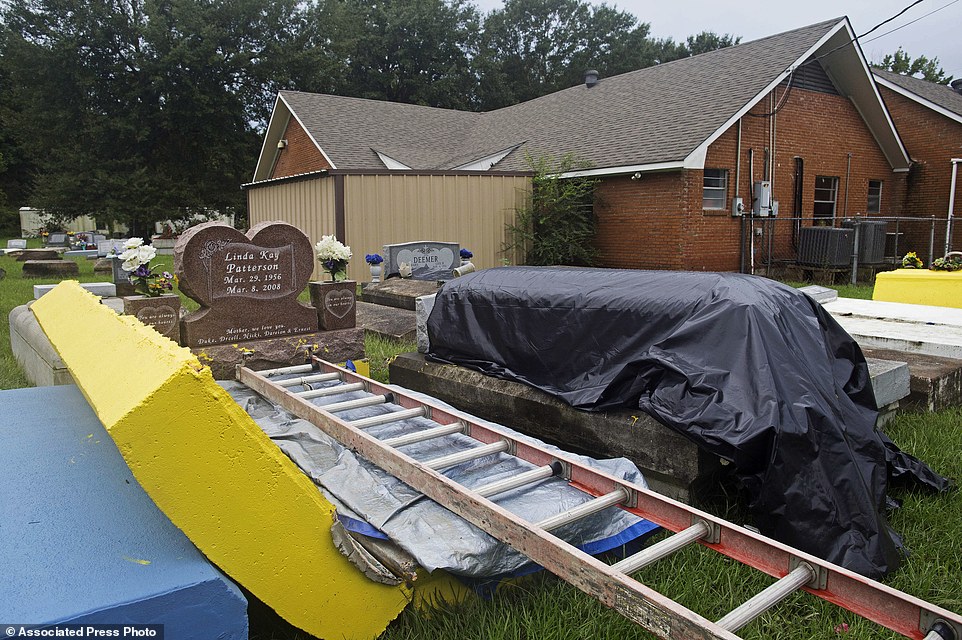 A coffin outside a flood damaged tomb is covered to be resealed at the cemetery of Greater St. Mark Baptist Church in Walker