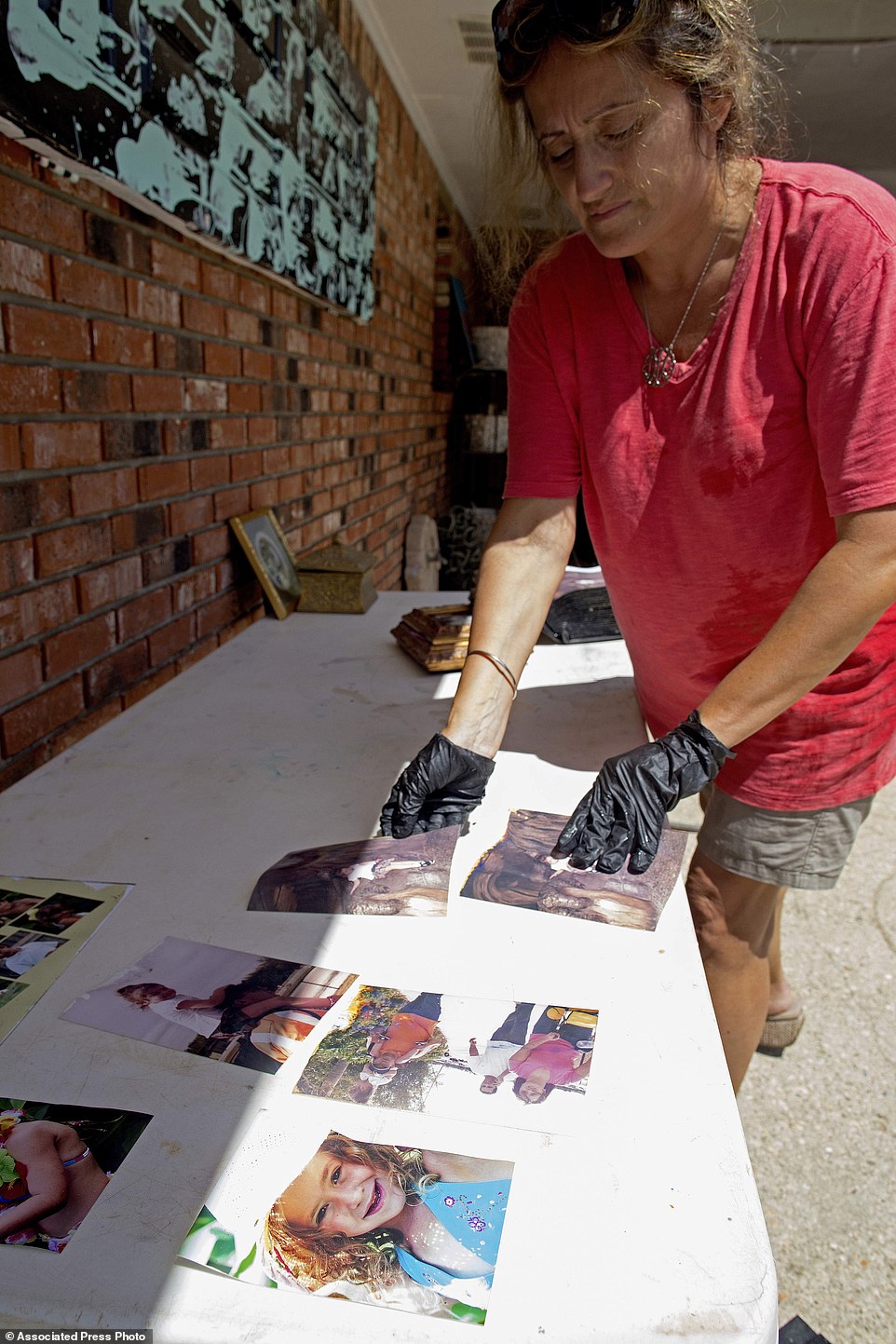 Daniella Letelier puts wet family photos out to dry as she cleans her Baton Rouge home damaged in the flood