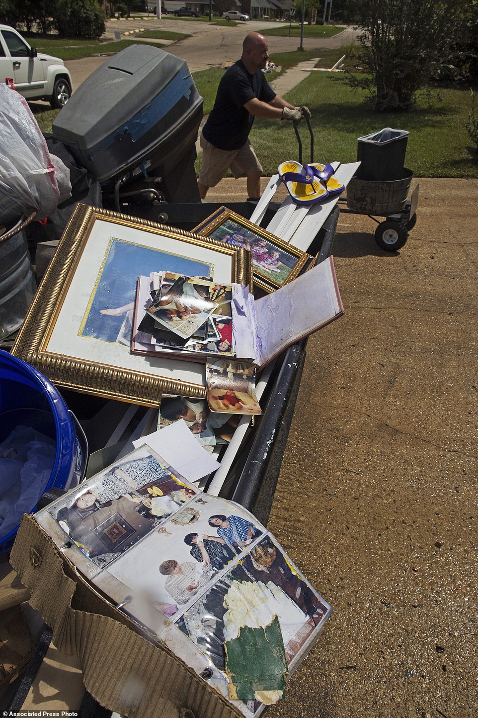 Family photos of the Lieteau family dry in the sun as family friend Danny Lemoine, 48, moves a cart with a trash can
