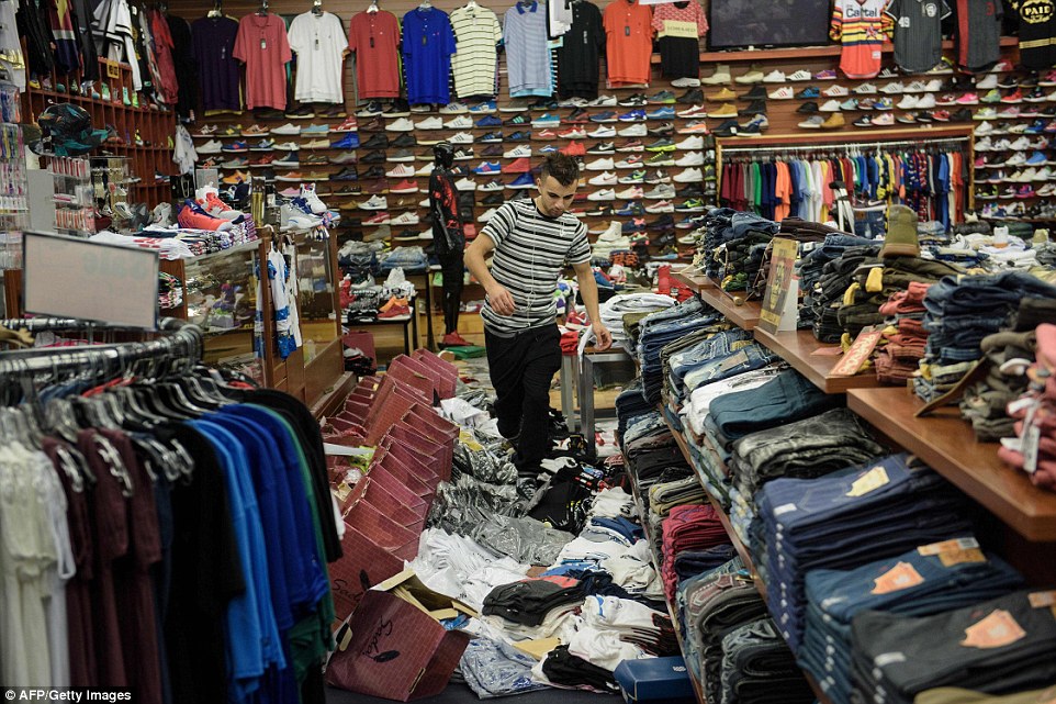 Mehmoud Elodeh walks over damaged merchandise as he checks on a clothing and shoe store  following the floods on Tuesday in Baton Rouge