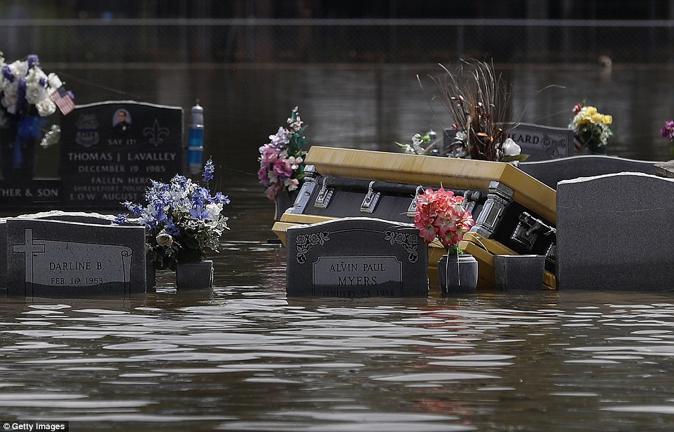 A casket is seen floating among graves adorned with flowers in a flooded cemetery on Wednesday in Sorrento, Louisiana